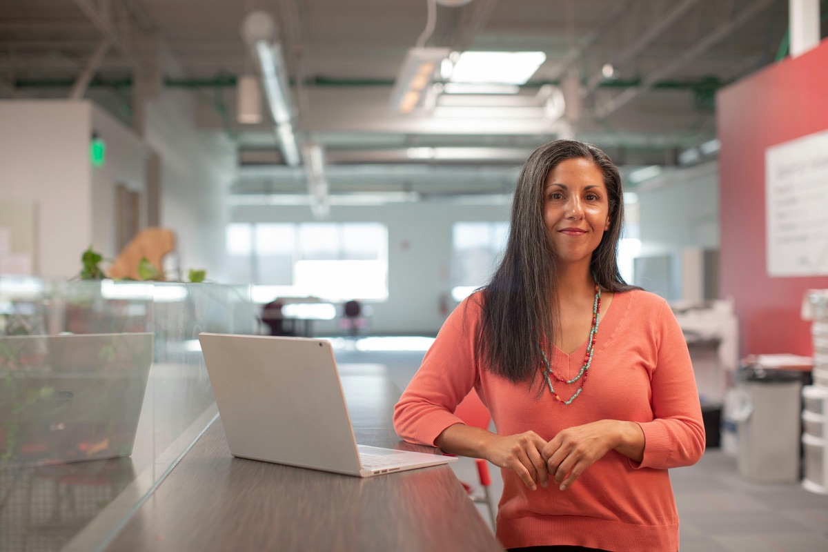 A small business owner standing beside her laptop in her workspace